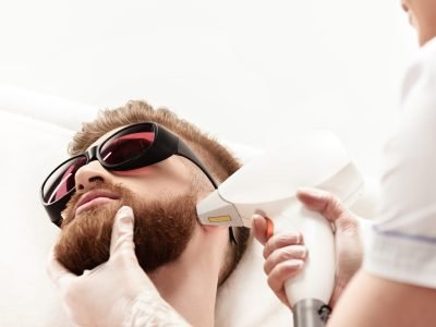 young man receiving laser skin care on face isolated on white. healthy lifestyle man concept